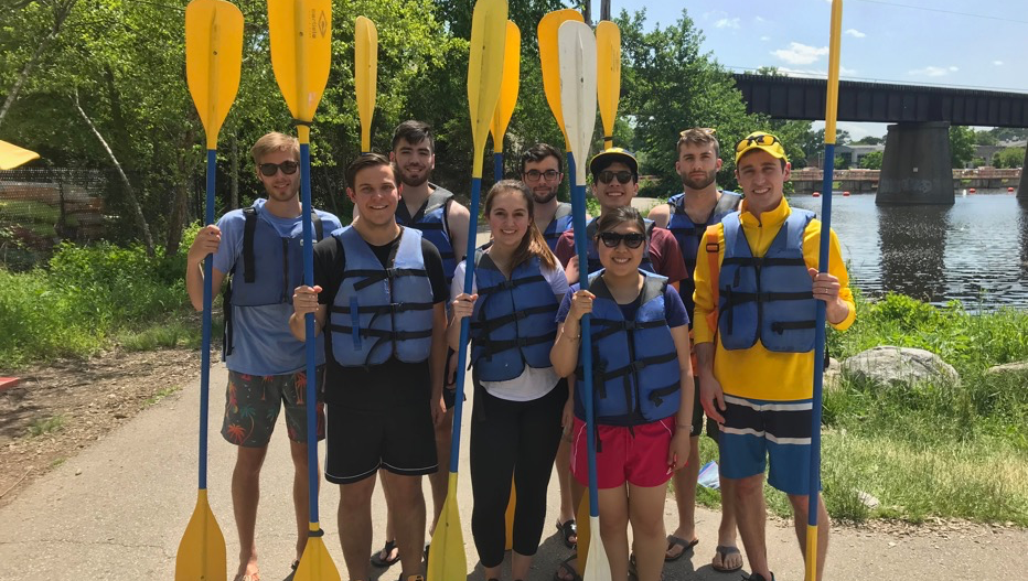 The team wearing life vests and holding kayaking oars
