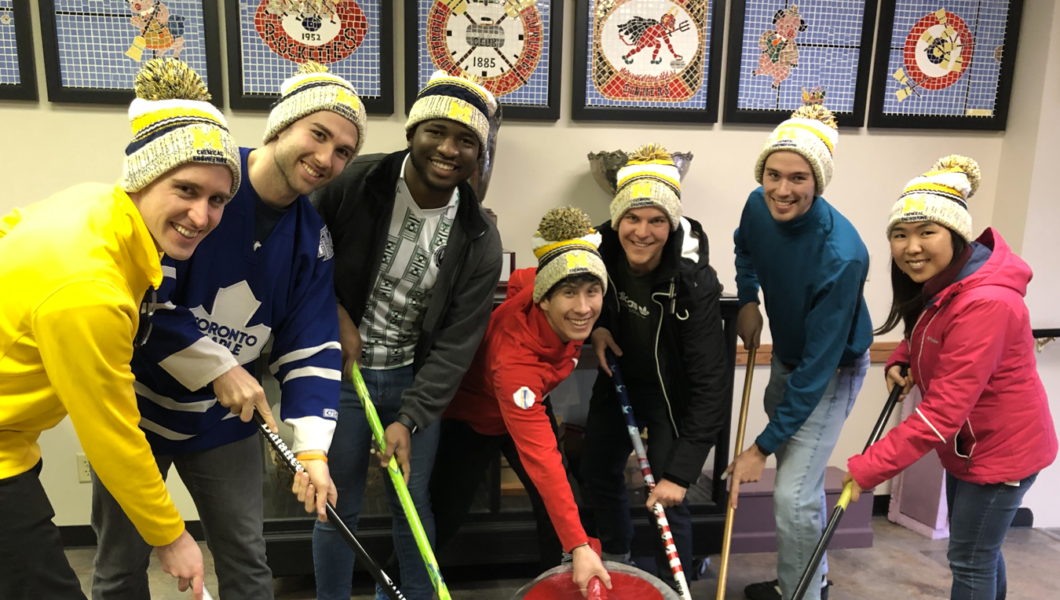 Group photo of the team with curling sticks